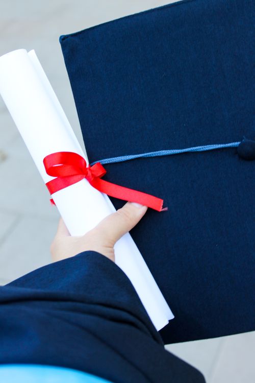 Ruka drži diplomu i akademsku kapu