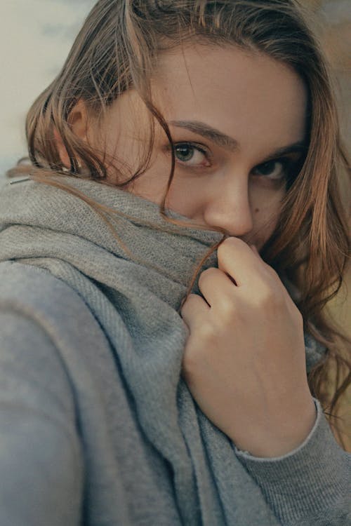 Close-Up Shot of a Woman Covering Her Face with Gray Sweater