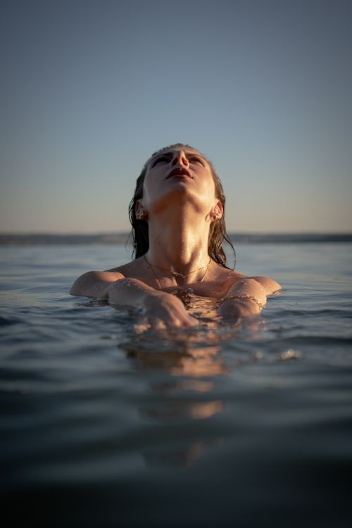 Free A serene moment capturing a woman immersed in the sea during sunset, evoking tranquility and freedom. Stock Photo