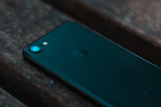Detailed close-up of a smartphone on a wooden plank, showcasing modern technology in a still life setting.