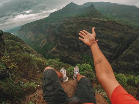 A person relaxing at the edge of a mountain cliff, enjoying breathtaking views of the valley below.