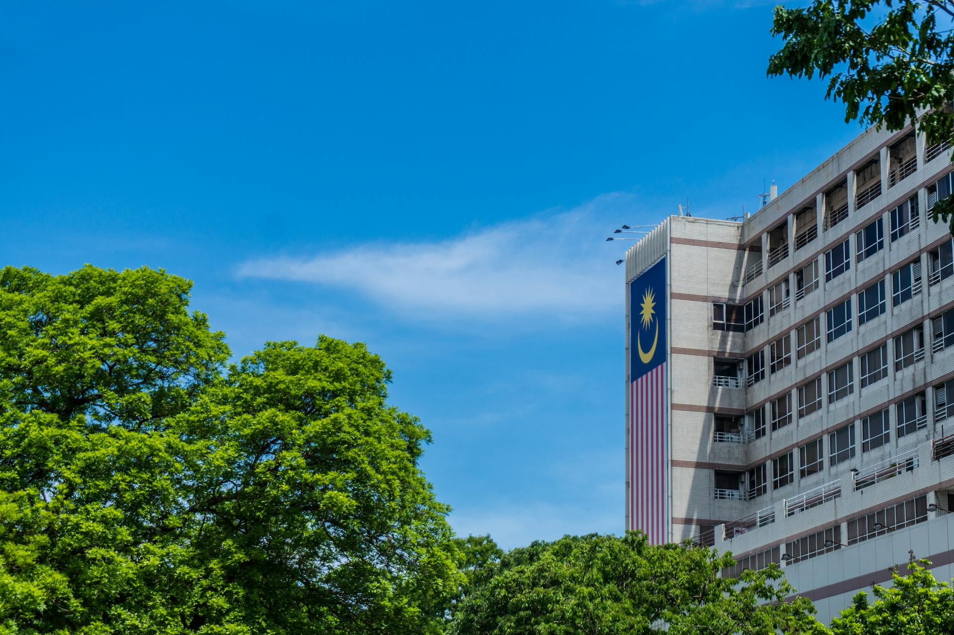 Modern architectural building with Malaysian flag and greenery in Kota Kinabalu, Sabah, Malaysia.