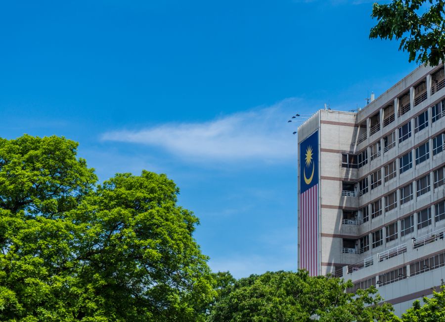 Modern architectural building with Malaysian flag and greenery in Kota Kinabalu, Sabah, Malaysia.