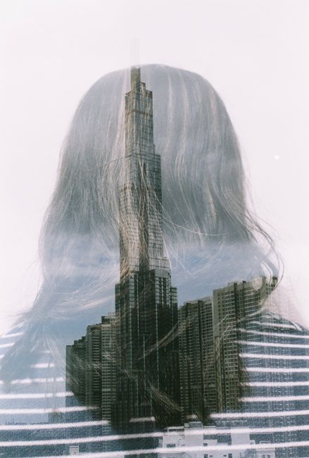 Creative double exposure photograph combining a city skyline and the silhouette of a woman from behind.