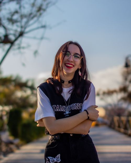 Free Chic young woman with glasses and red lips smiling in a sunny Spanish urban setting. Stock Photo