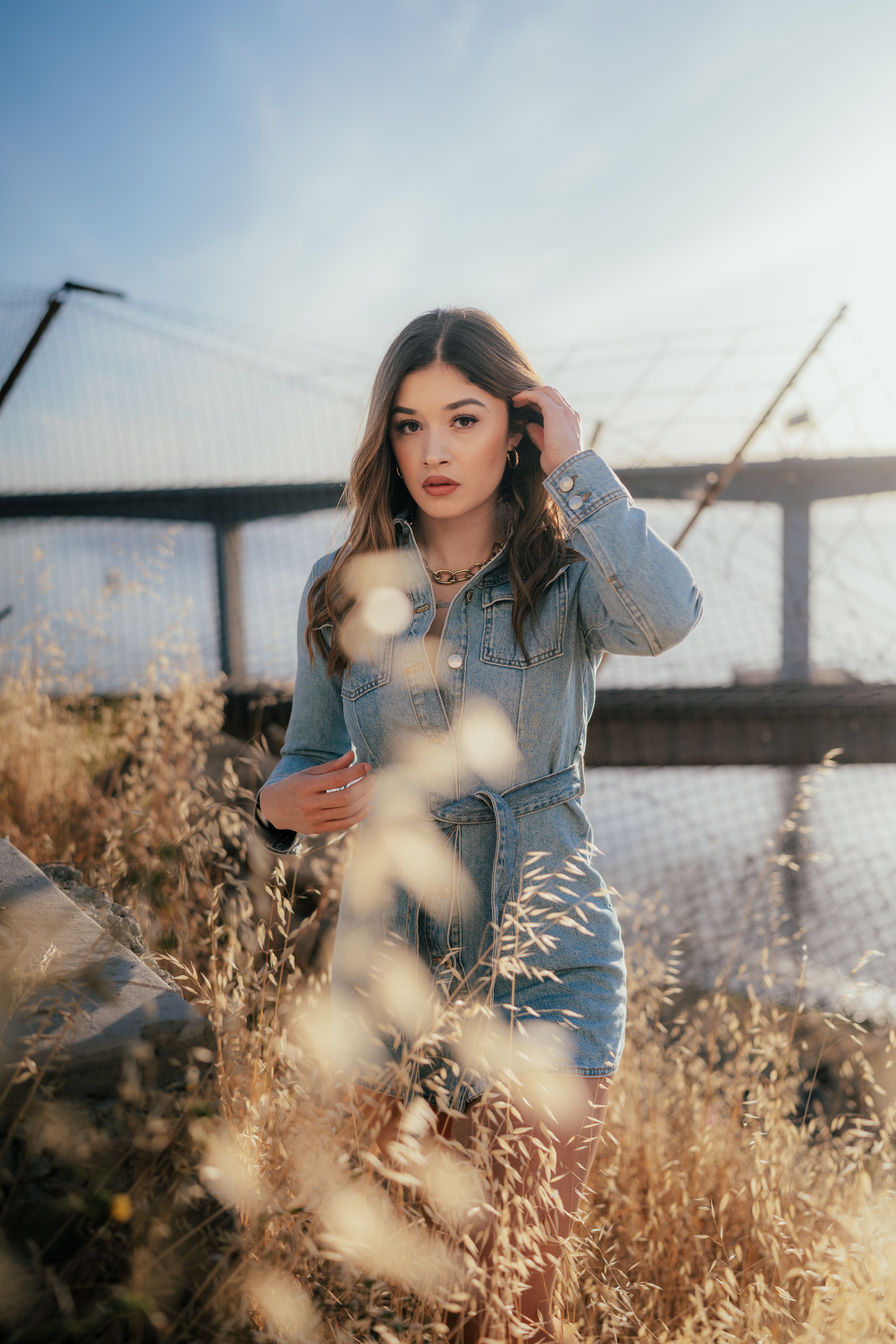 A Woman in Denim Dress Standing on Brown Grass · Free Stock Photo