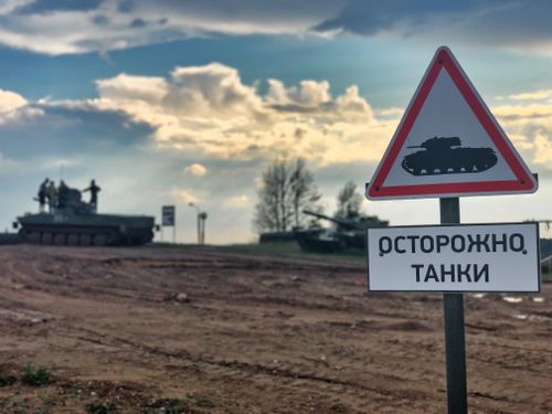 Free Military tanks in Belarus with a warning sign for caution on dirt road. Stock Photo