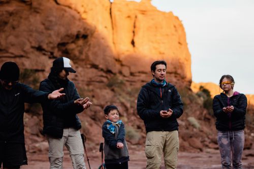 Free A diverse group meditates in the tranquil desert sunrise, embracing peaceful reflection. Stock Photo