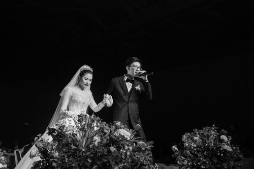 Free A romantic moment of an Asian couple singing at their wedding reception in a monochrome setting. Stock Photo