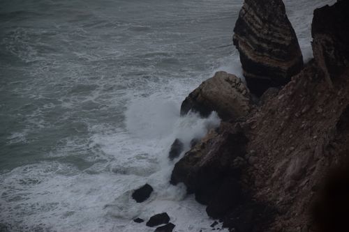 Free Powerful ocean waves striking rocky coast at twilight, capturing nature's raw force. Stock Photo