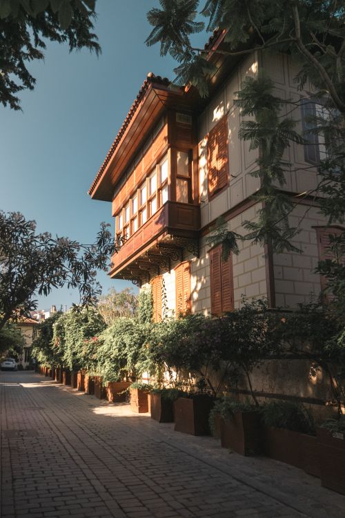 Free Charming historical villa with wooden balconies and lush greenery in an idyllic street setting. Stock Photo