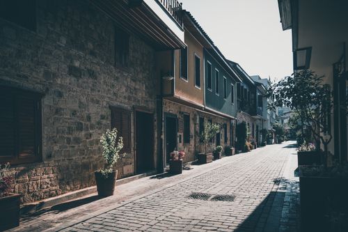 Free A picturesque cobblestone alley lined with historic houses and vibrant potted plants. Stock Photo