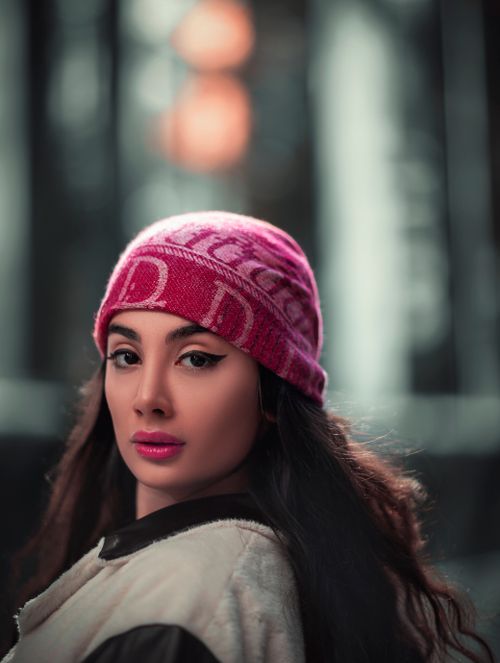 Free Close-up portrait of a woman wearing a red beanie with dark curly hair, looking back. Stock Photo