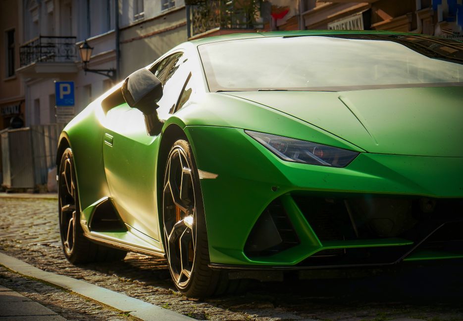 Detailed shot of a sleek green sports car parked on a sunny street, showcasing its modern design.