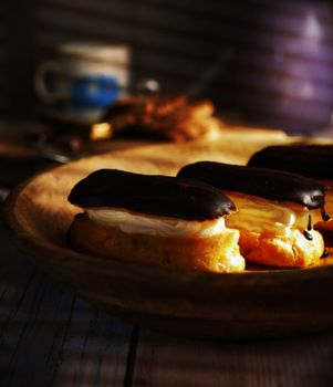 Delicious chocolate-covered eclairs on a wooden plate, perfect for dessert lovers.