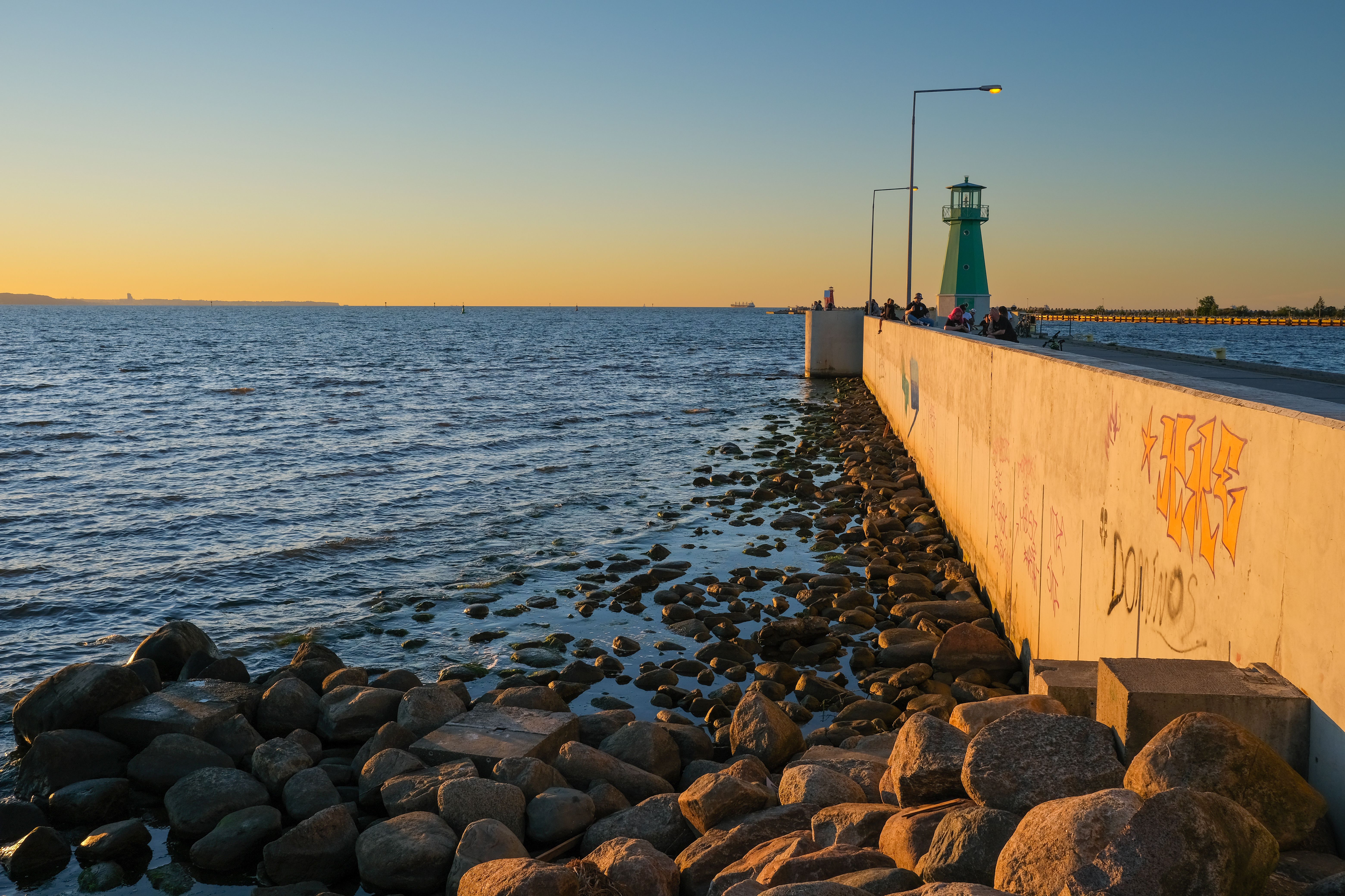Captivating sunset view of a lighthouse by the rocky shore in Gdańsk, Poland. — Trójmiasto