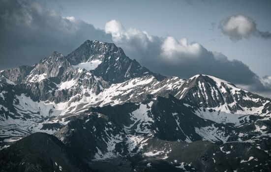 Breathtaking view of snow-capped mountains under a cloudy sky in Tirol, Austria.