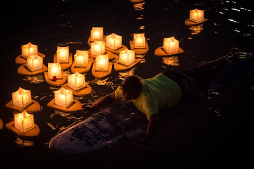 Mann Reitet Auf Surfbrett Nahe Papierlaternen Auf Gewässer Während Der Nacht
