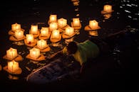 在夏威夷檀香山，有人望着照亮夜水的浮灯