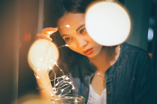 Woman In Blue Denim Jacket Holding String Lights