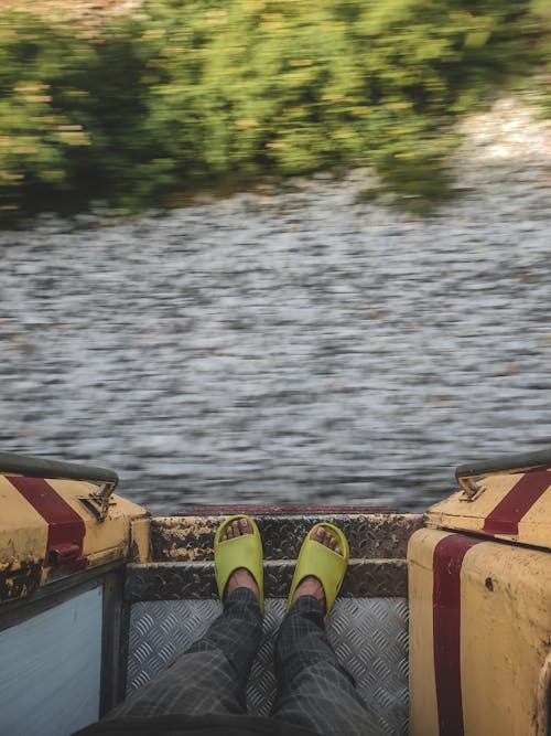 Person Wearing Slippers Standing at the Doorway of a Moving Train