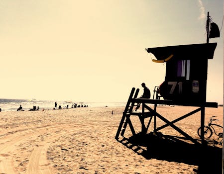 Silhouette of a person on a lifeguard tower at Newport Beach with a sandy seashore.