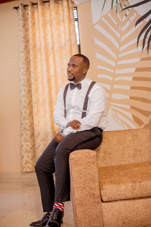 Free Fashionable African American man wearing suspenders and bow tie, sitting on a sofa indoors. Stock Photo