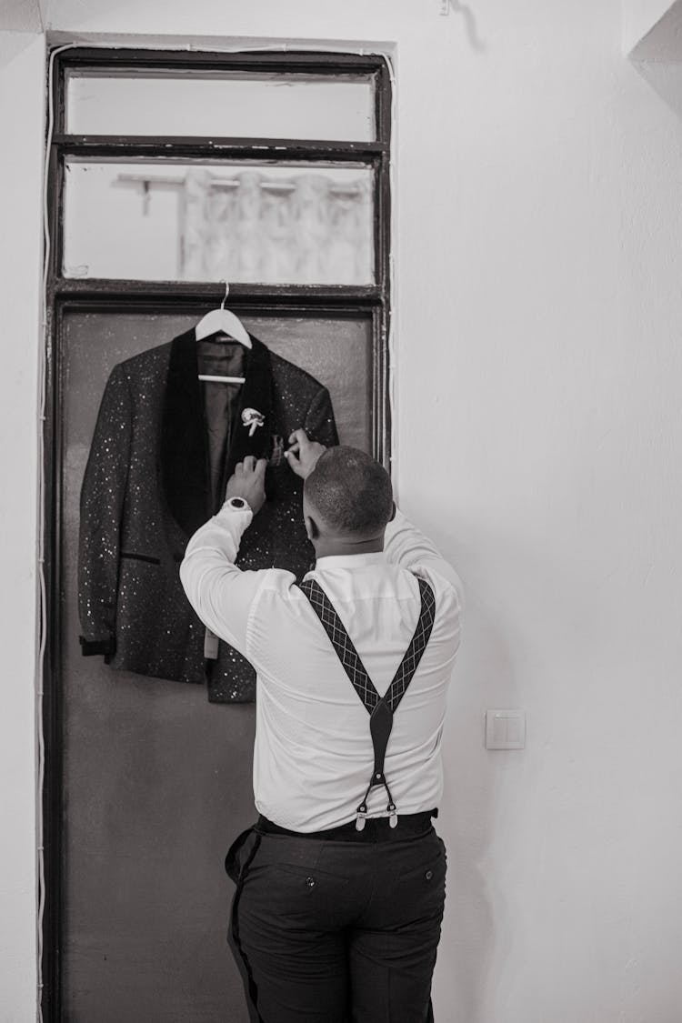 Back View Shot Of A Man Fixing The Hanging Suit