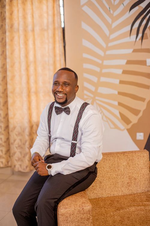 Free Portrait of a smiling man in suspenders, sitting indoors on a sofa. Stock Photo