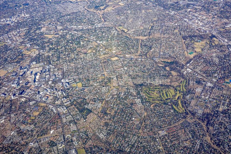 High altitude aerial photo showing dense urban cityscape with roads and green parks.