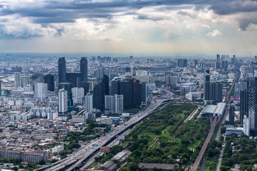 Aerial cityscape showing modern skyscrapers and urban landscape under a cloudy sky.