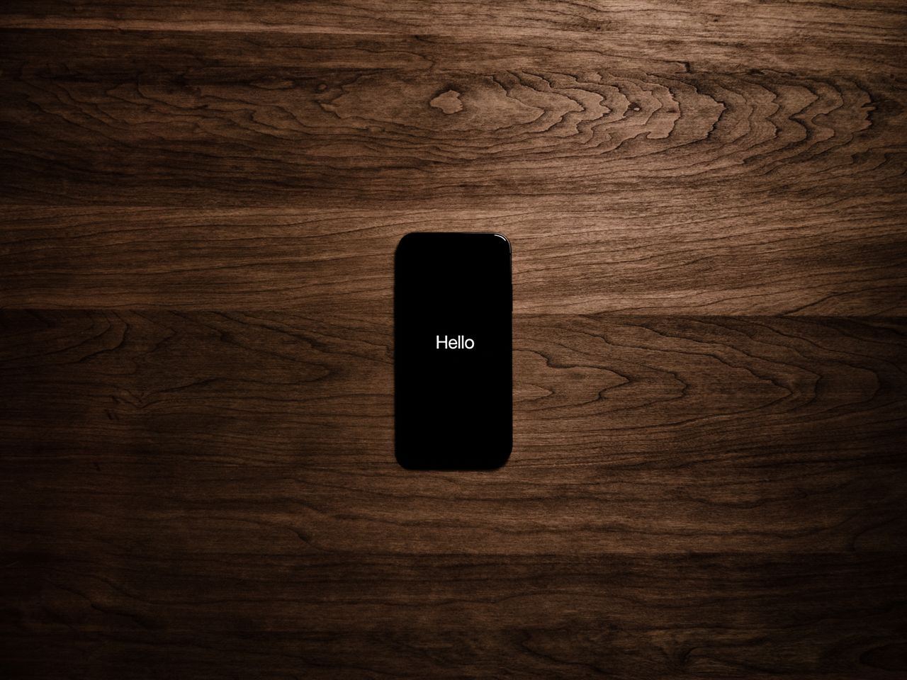 a smartphone displays hello against a dark wooden background offering