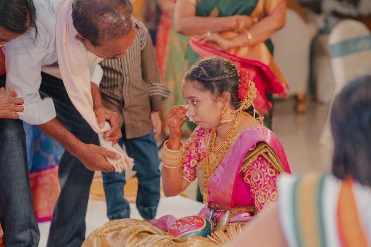 A Woman In Pink Sari Wiping Her Tears Away