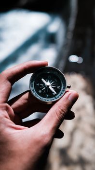 Close-up of a hand holding a compass, symbolizing navigation and exploration outdoors.