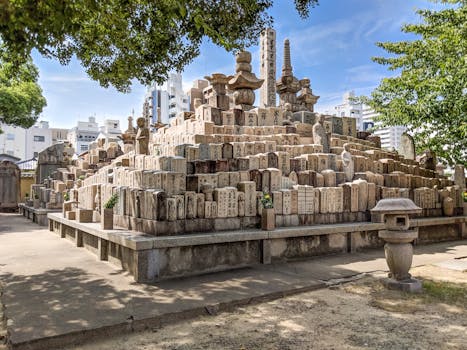 A serene view of historic gravestones in an Osaka temple under a clear sky.