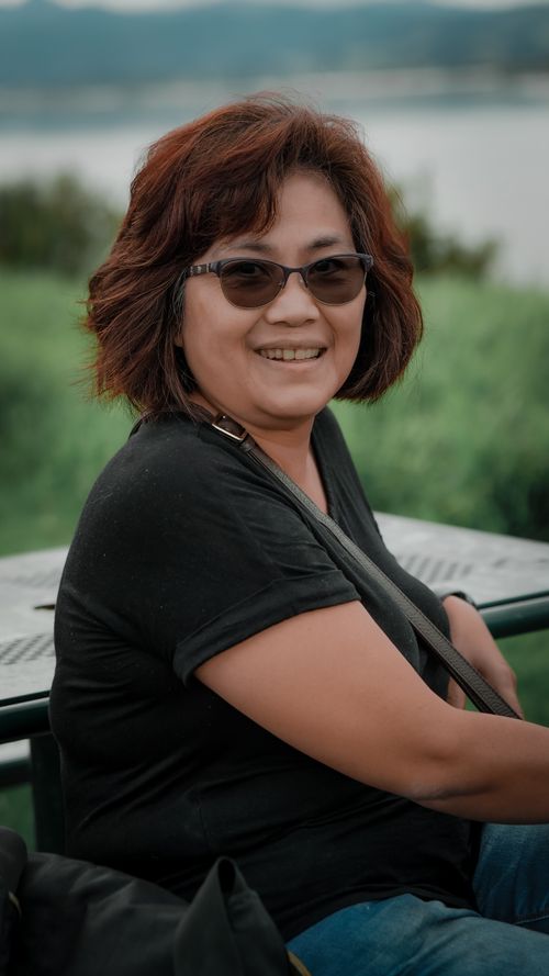 Free Smiling woman in sunglasses enjoying a sunny day outdoors at a scenic location. Stock Photo