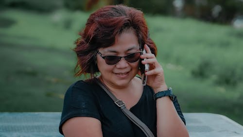 A Woman in Black Shirt Talking on the Phone