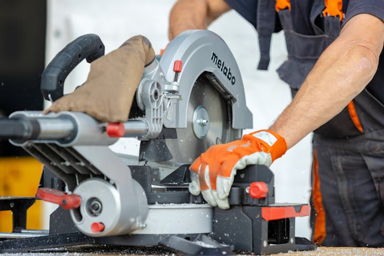 Worker Cutting A Metal Beam With A Saw