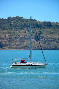 A sailboat cruises peacefully on a bright summer day, ideal for leisure travel.