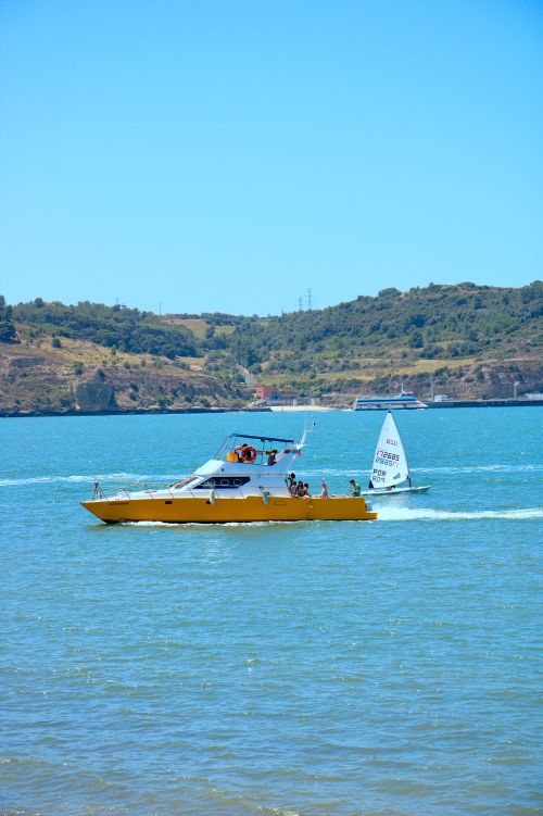 Free A vibrant yellow boat navigating the picturesque sea under a clear blue sky, perfect for summer adventure. Stock Photo