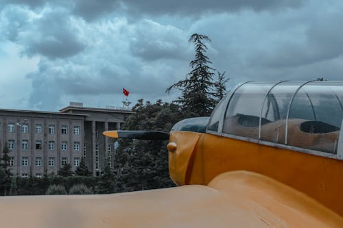 Yellow Airplane Near Gray Concrete Building