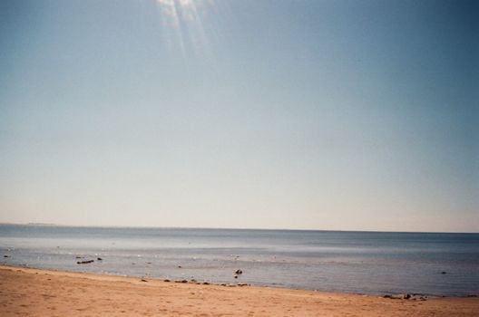 A tranquil summer beach scene in Finland, capturing vast sky and calm sea.