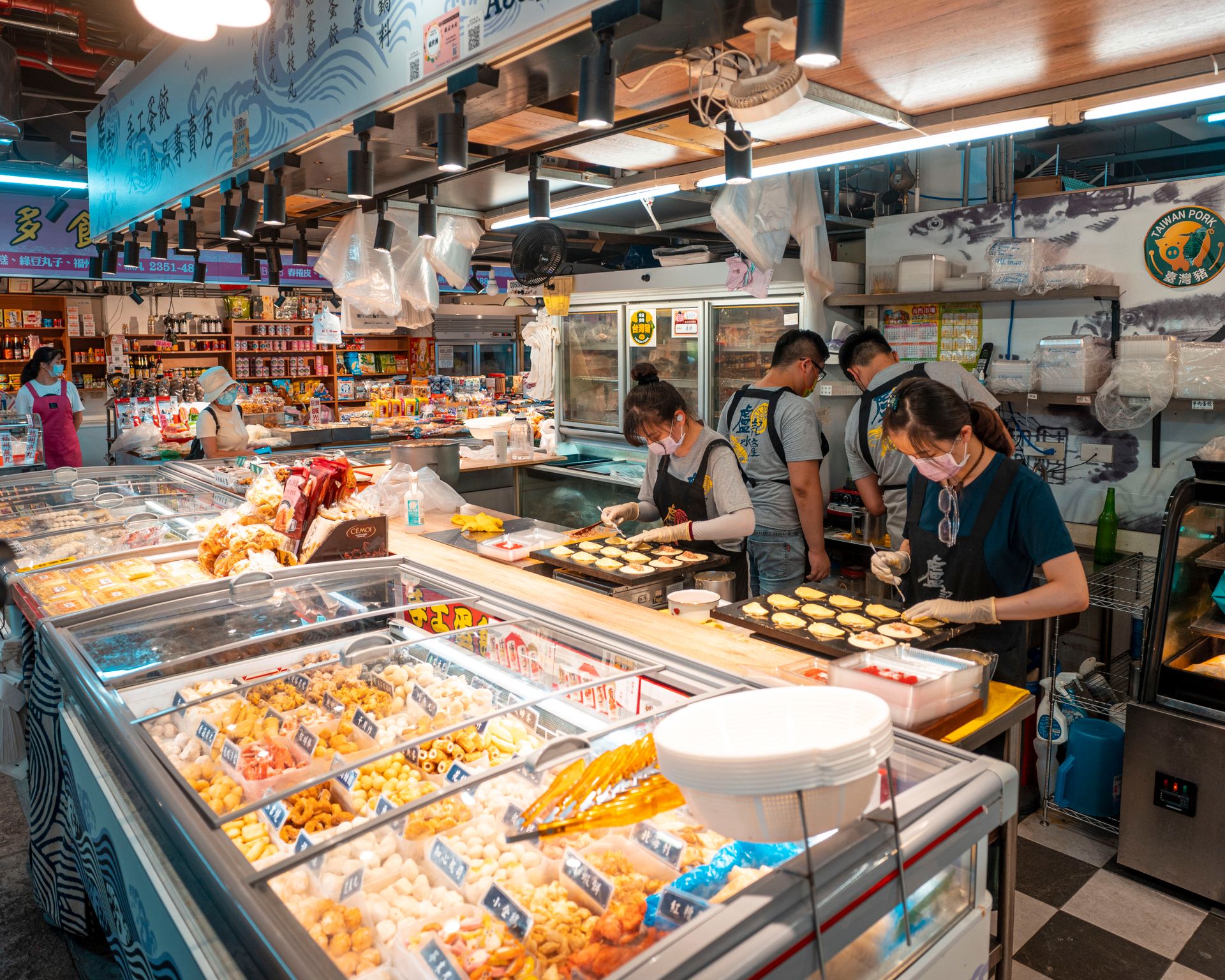 Busy Asian market scene with shoppers and food displays, showcasing a vibrant indoor setting.