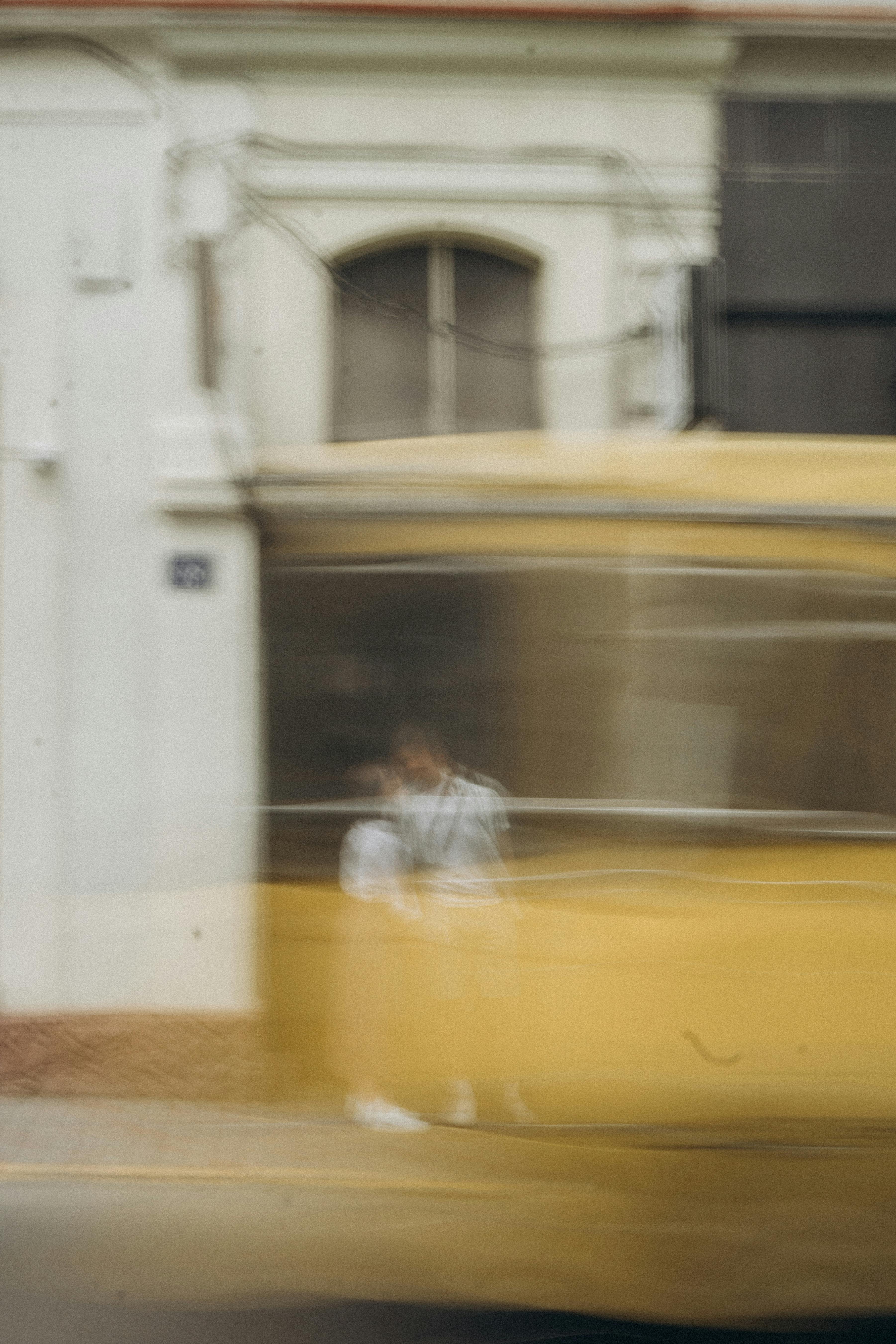 Blurred city street scene featuring a moving tram and couple, captured with artistic long exposure.