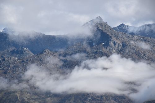 Free Dramatic landscape of rocky mountains shrouded in fog and clouds, creating a mystical atmosphere. Stock Photo