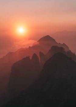 Dramatic sunset over silhouetted mountain peaks in Piani Resinelli, Italy, creating a serene landscape.