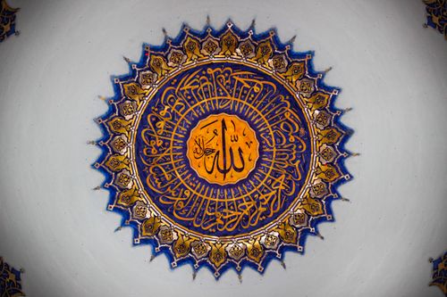 Free A close-up of detailed Islamic calligraphy on a mosque dome featuring blue and gold patterns. Stock Photo
