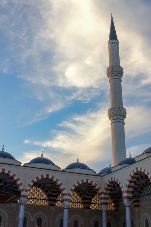 Free A beautiful view of the Camlica Mosque minaret and arches under a vibrant sunset sky. Stock Photo