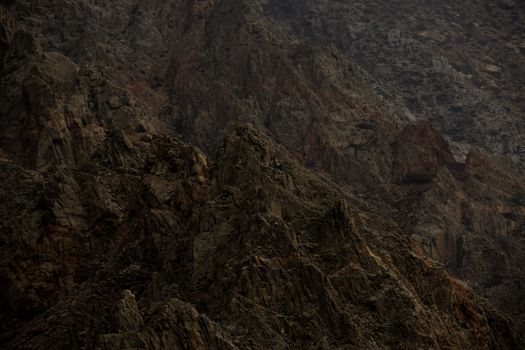 Dark, moody rocky mountains capturing the rugged beauty and texture of natural formations at dusk.