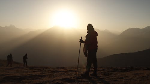 Silhouette of Traveller with Walking Stick against Sunlight